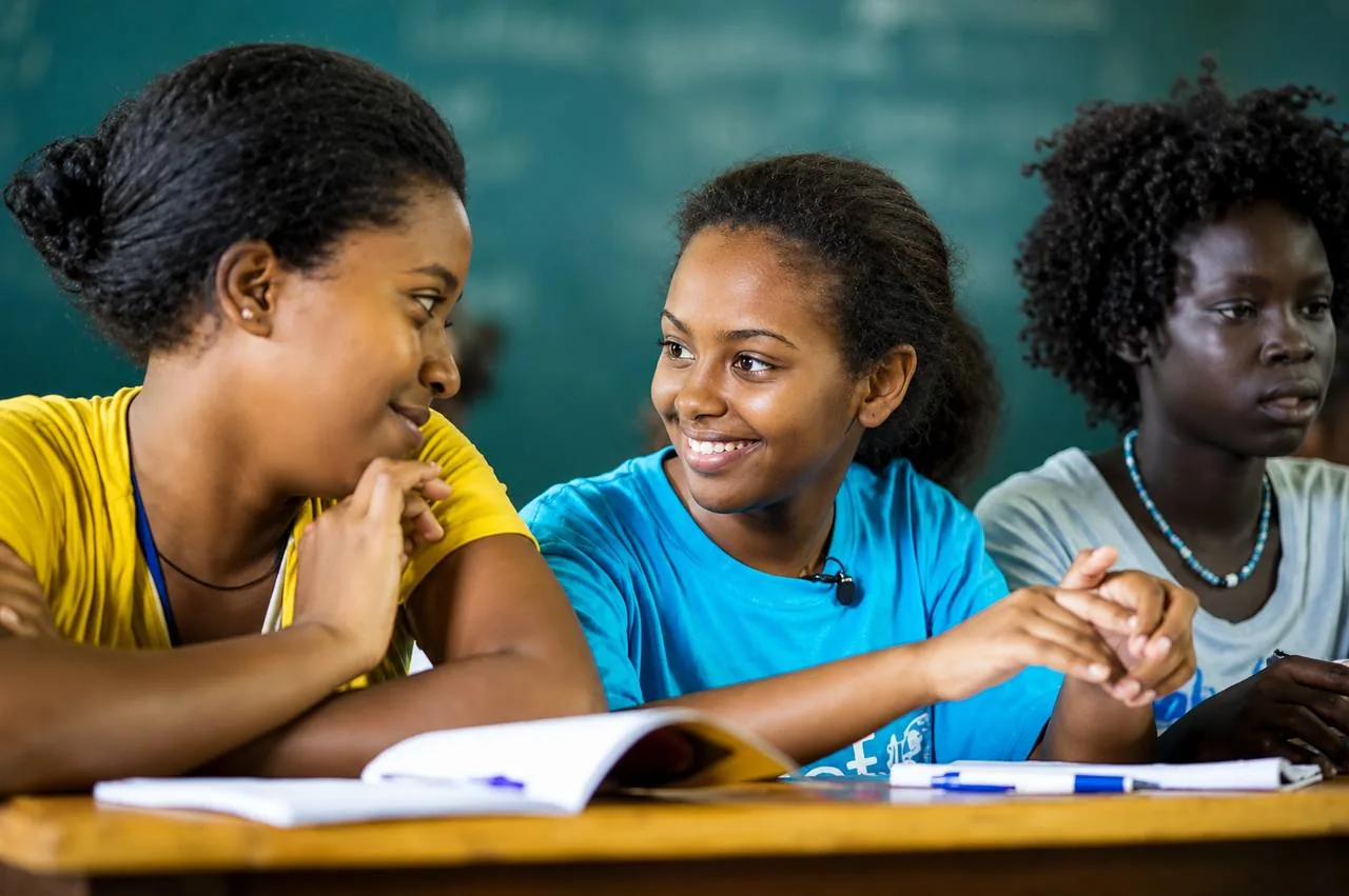 A volunteer mentor talking with a student over an open notebook